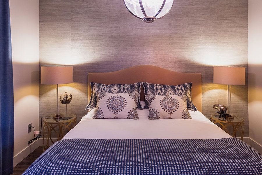 A bedroom with a bed , two lamps and a chandelier.