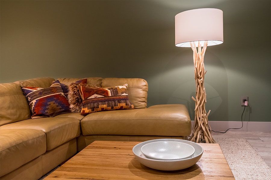 A living room with a couch , table , lamp and bowl on the table.