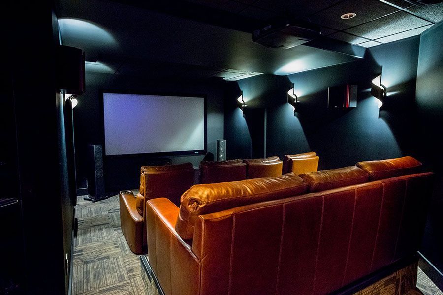A home theater with a couch and chairs and a large screen.