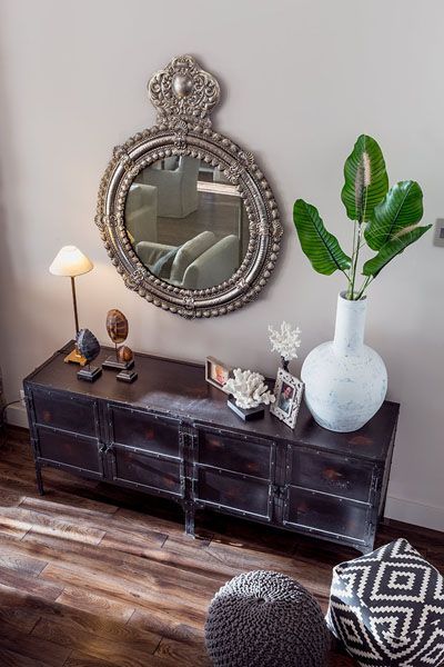 A living room with a dresser and a mirror on the wall
