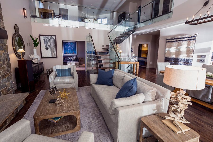 A living room with a couch , chairs , coffee table and stairs.