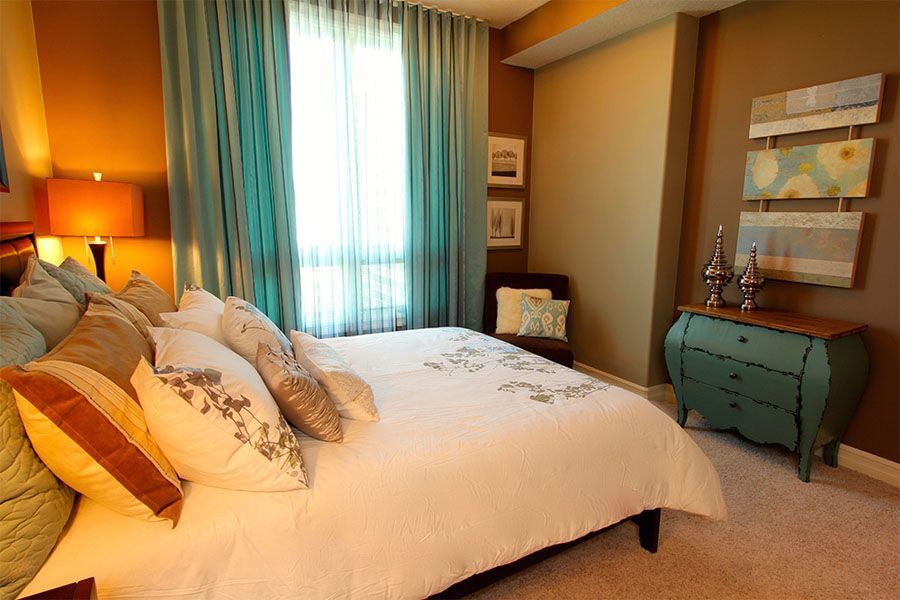 A bedroom with a bed , dresser , chair and window.