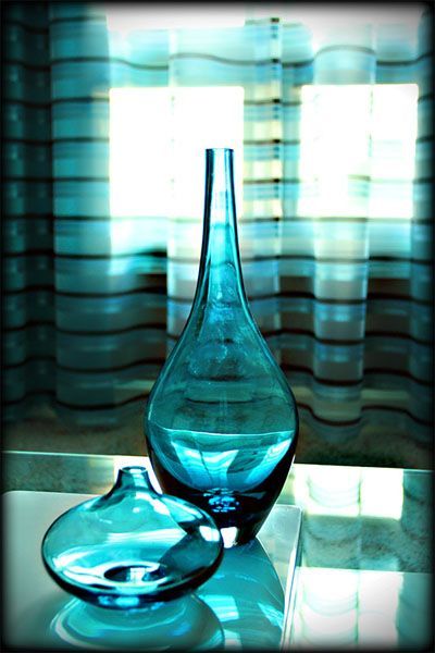 Two blue vases are on a table in front of a window