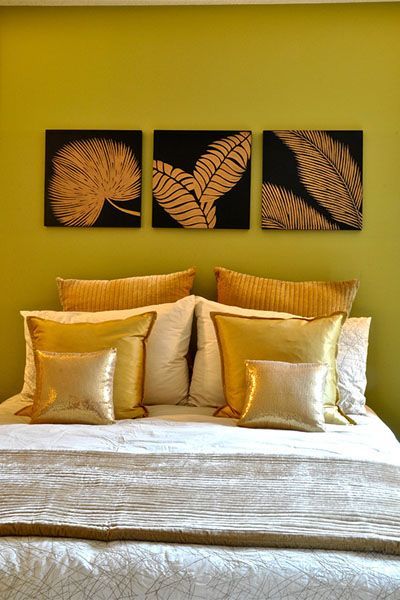 A bed with three paintings on the wall above it