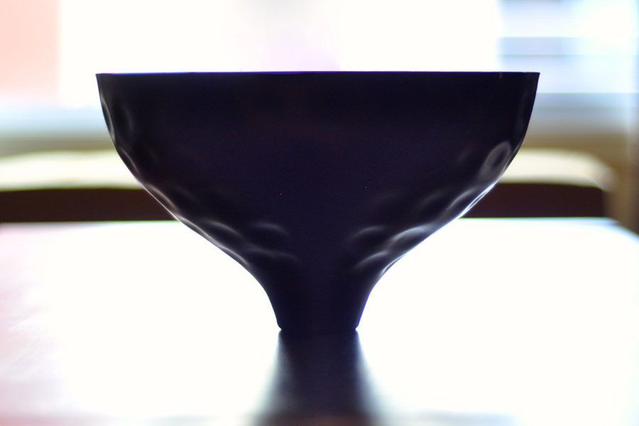 A black bowl is sitting on a table in front of a window