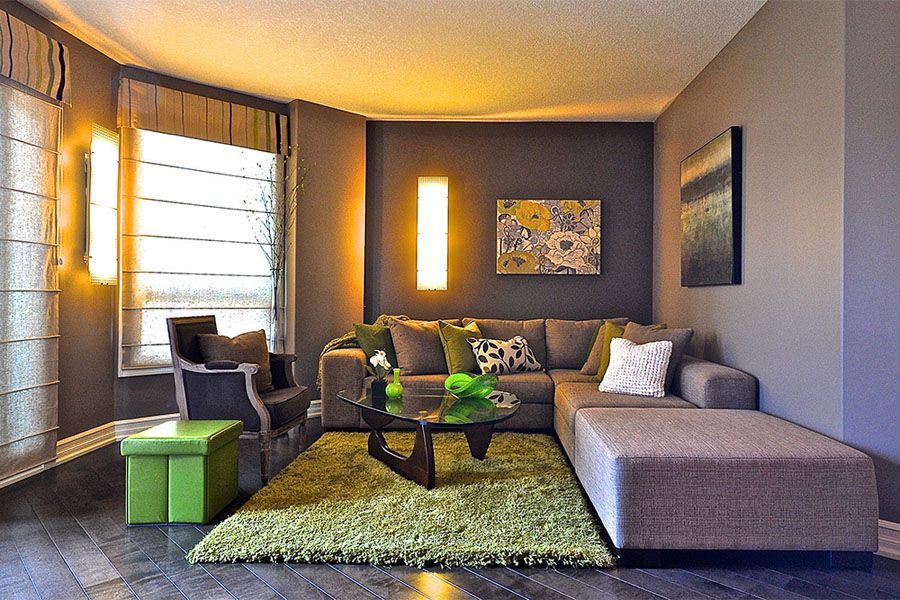 A living room with a sectional couch and a green rug