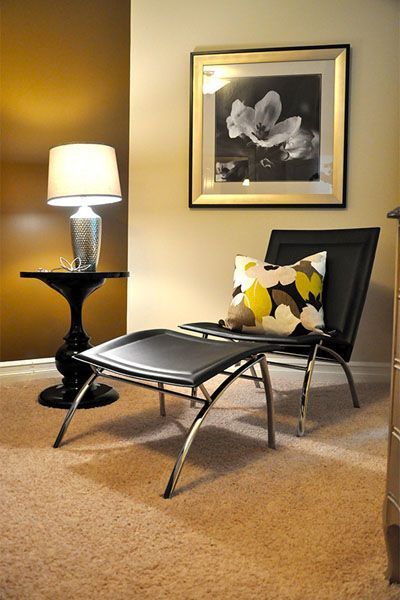 A living room with a chair and ottoman and a lamp