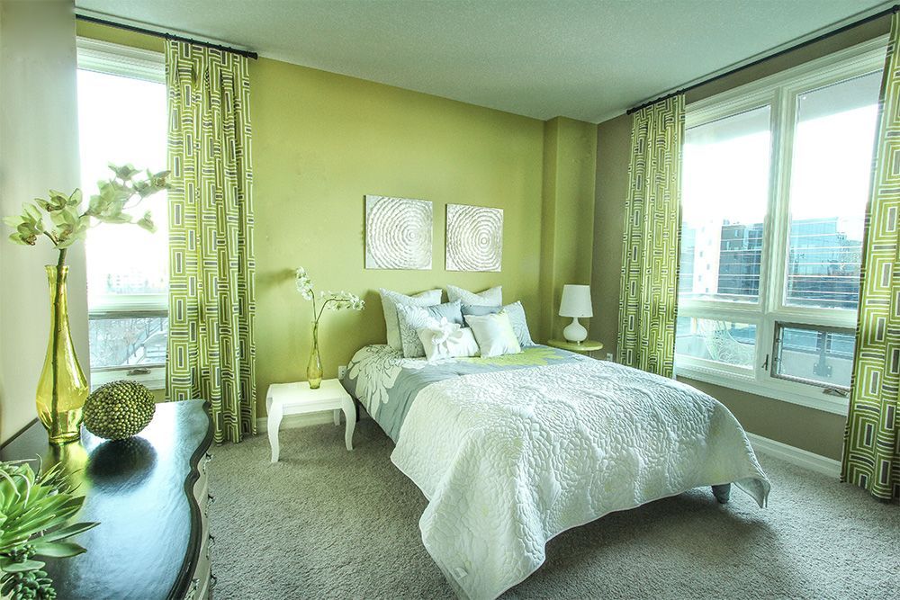 A bedroom with green walls and a white bed