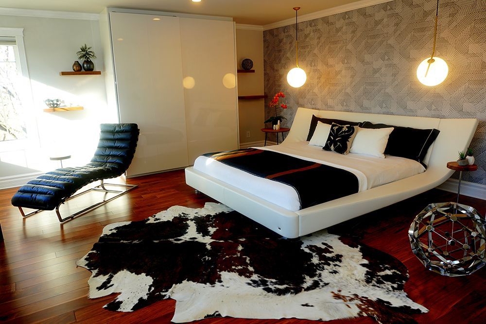 A bedroom with a large bed and a black and white cowhide rug