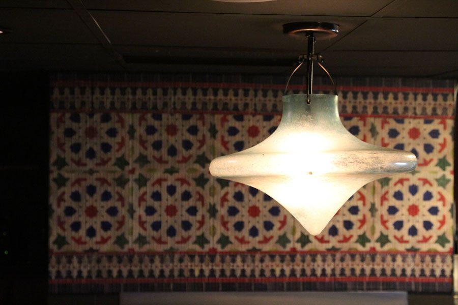 A light hanging from the ceiling in front of a colorful wall