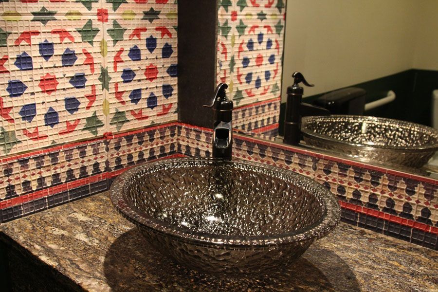 A bathroom with a sink and a mirror with a patterned wall