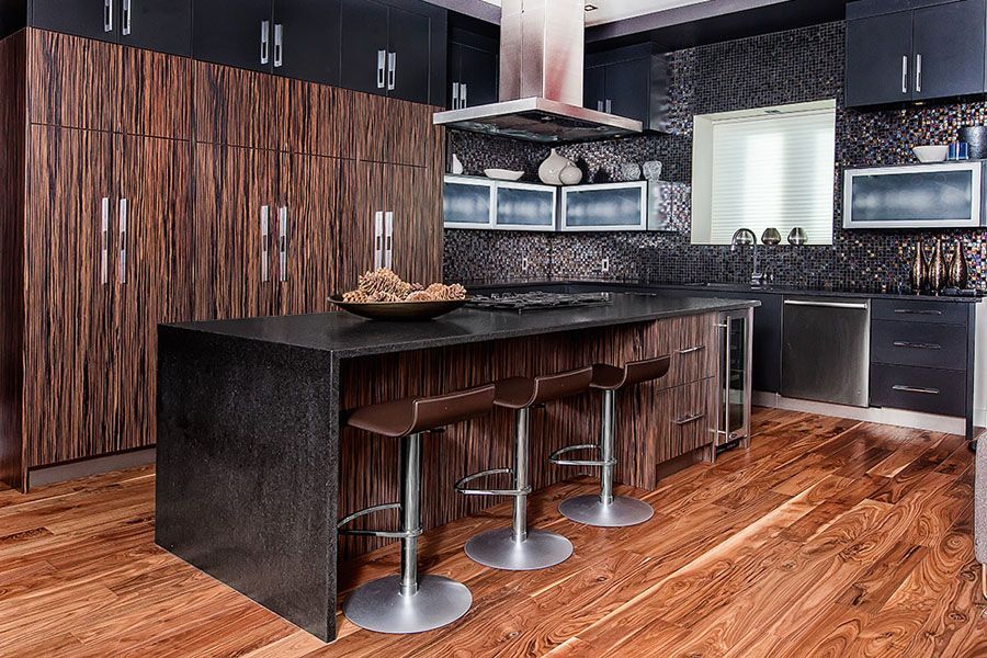 A kitchen with wooden floors and black cabinets