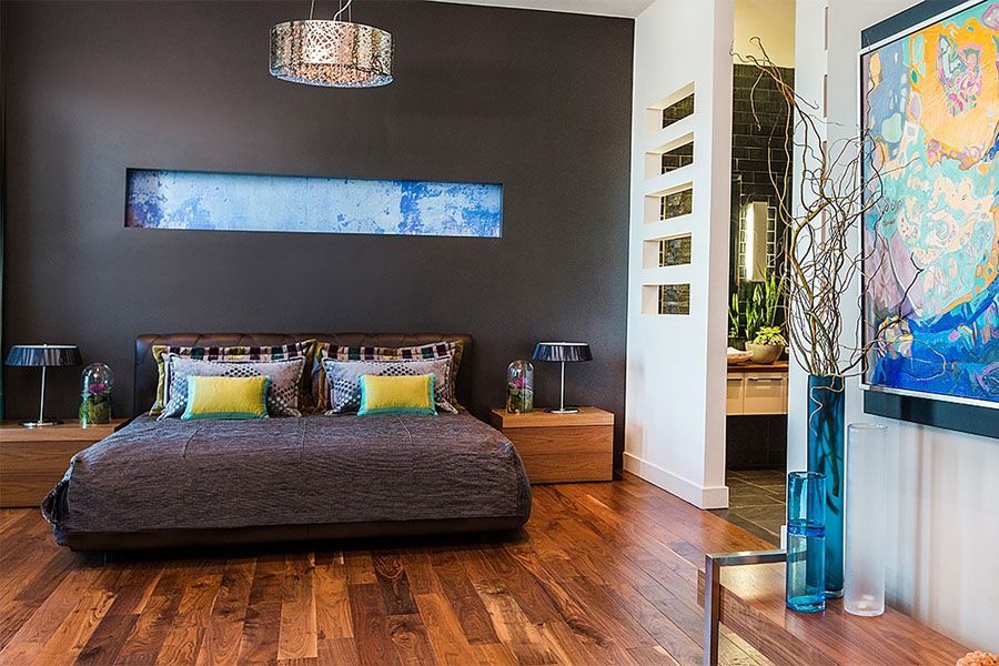 A bedroom with a bed , nightstands , lamps and a painting on the wall.