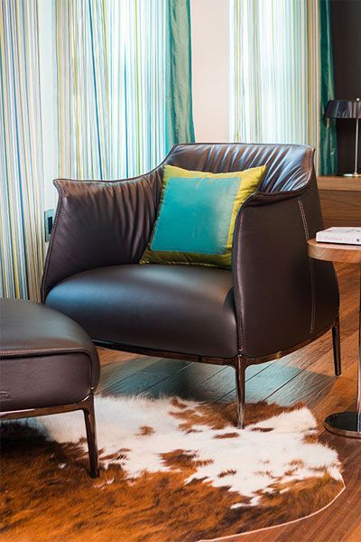 A living room with a chair and ottoman and a cowhide rug.