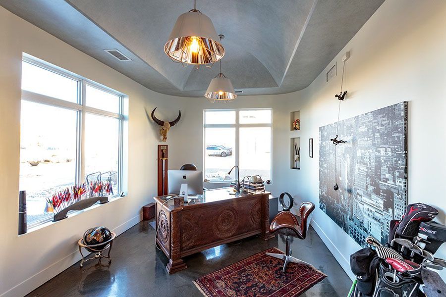 A home office with a desk , chair , motorcycle and a painting on the wall.
