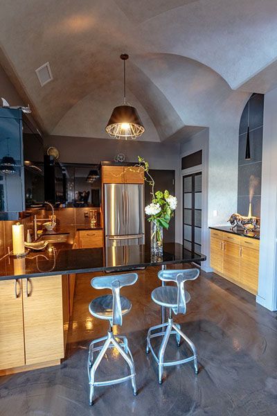 A kitchen with stools and a stainless steel refrigerator
