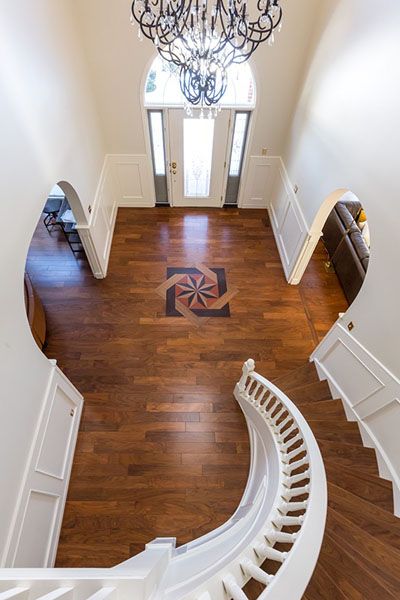 An aerial view of a curved staircase in a house with a chandelier hanging from the ceiling.