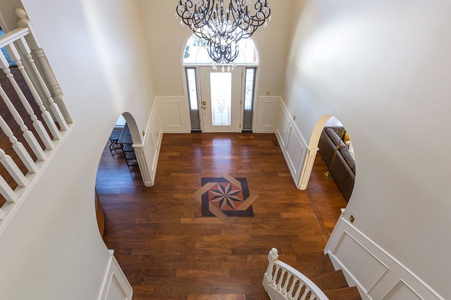 An aerial view of a large hallway with hardwood floors and a chandelier.