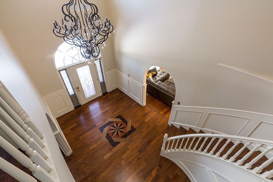 An aerial view of a staircase in a house with a chandelier hanging from the ceiling.