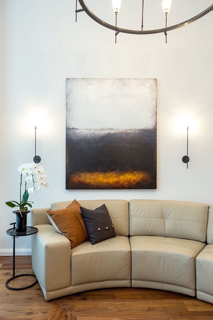 A living room with a couch and a painting on the wall.