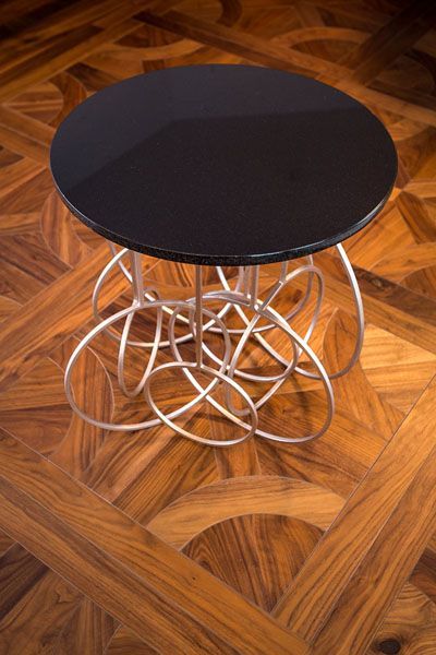 A round table with a black top sits on a wooden floor