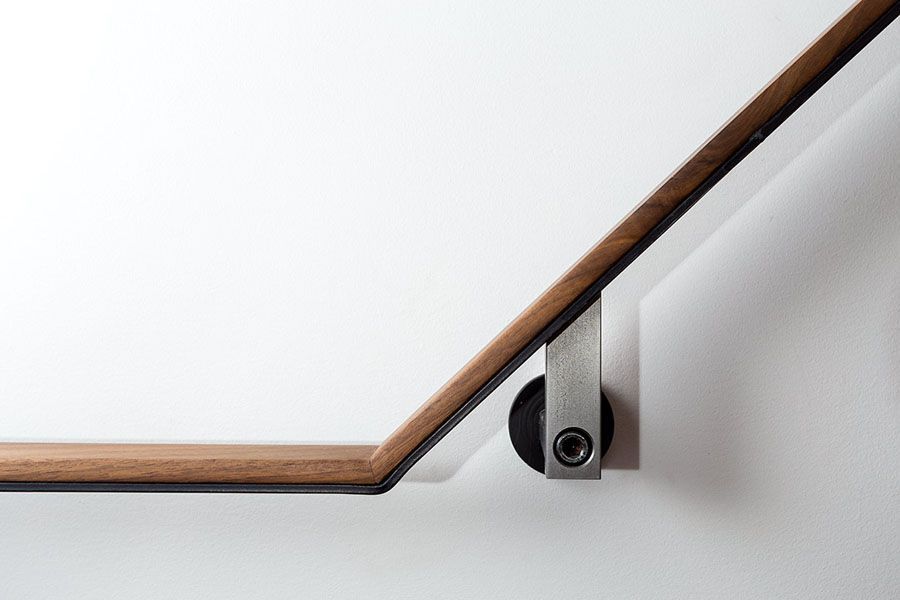 A close up of a wooden railing on a white wall.