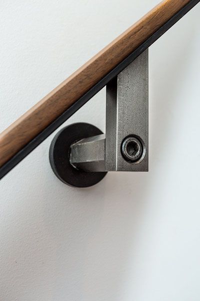 A close up of a handrail on a white wall.