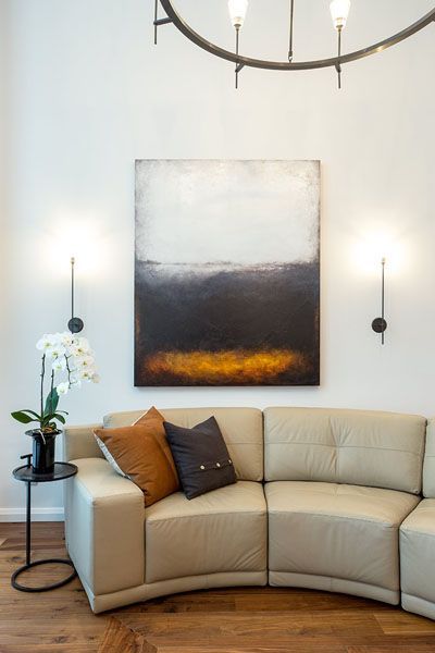 A living room with a curved couch and a painting on the wall.