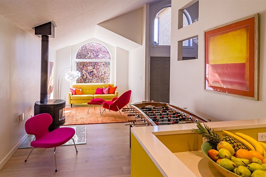 A living room with a yellow couch and pink chairs