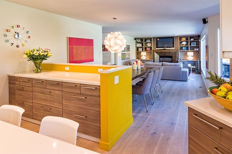 A kitchen with a yellow wall between the dining room and living room