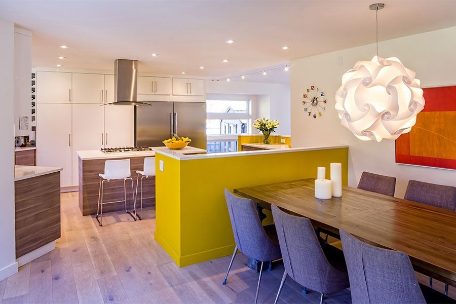 A kitchen with a yellow island and a clock on the wall
