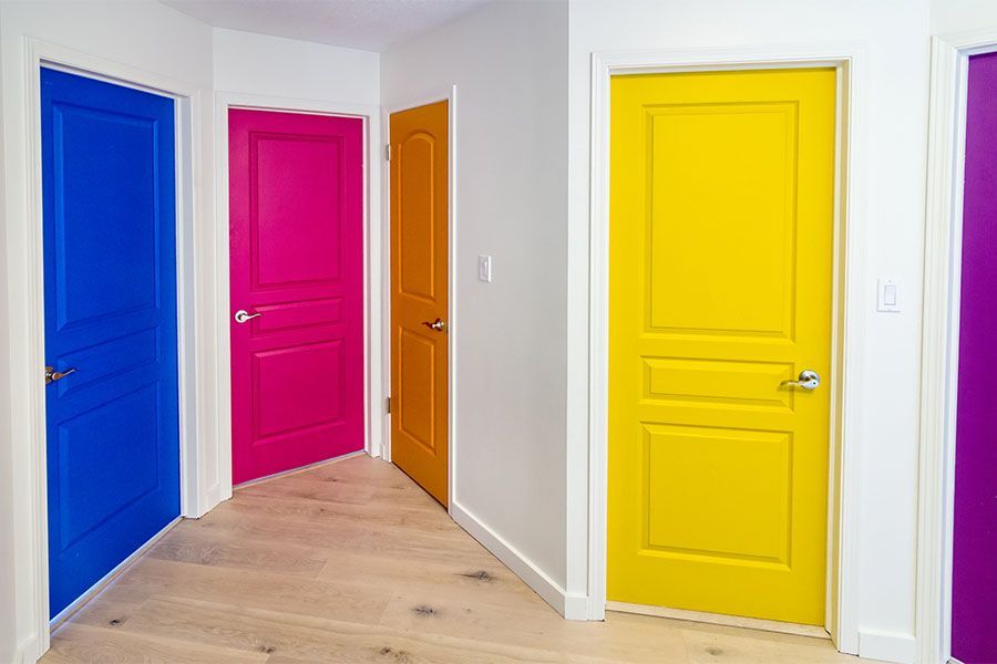 A hallway with four colorful doors painted different colors.