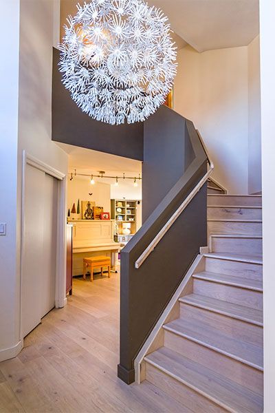 A spiral staircase in a house with a chandelier hanging from the ceiling.