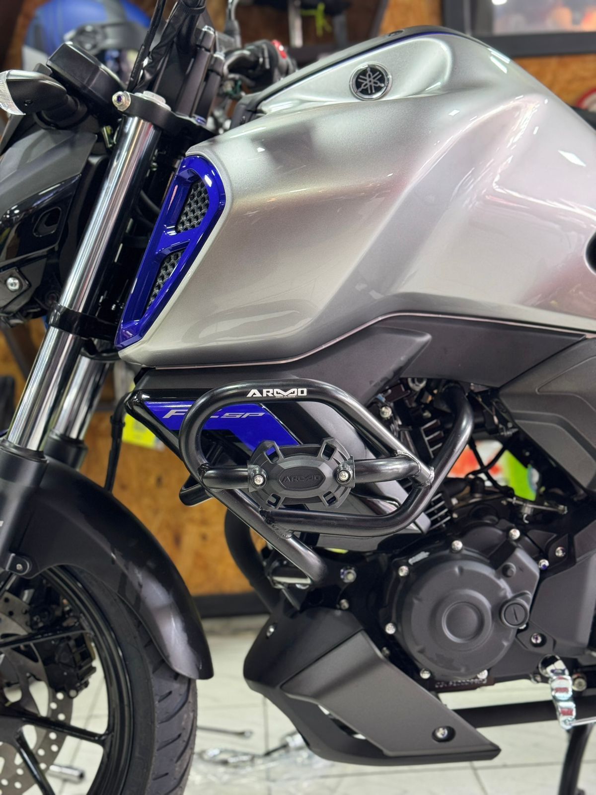 Motocicleta Yamaha plateada con protector de motor negro y detalles azules.