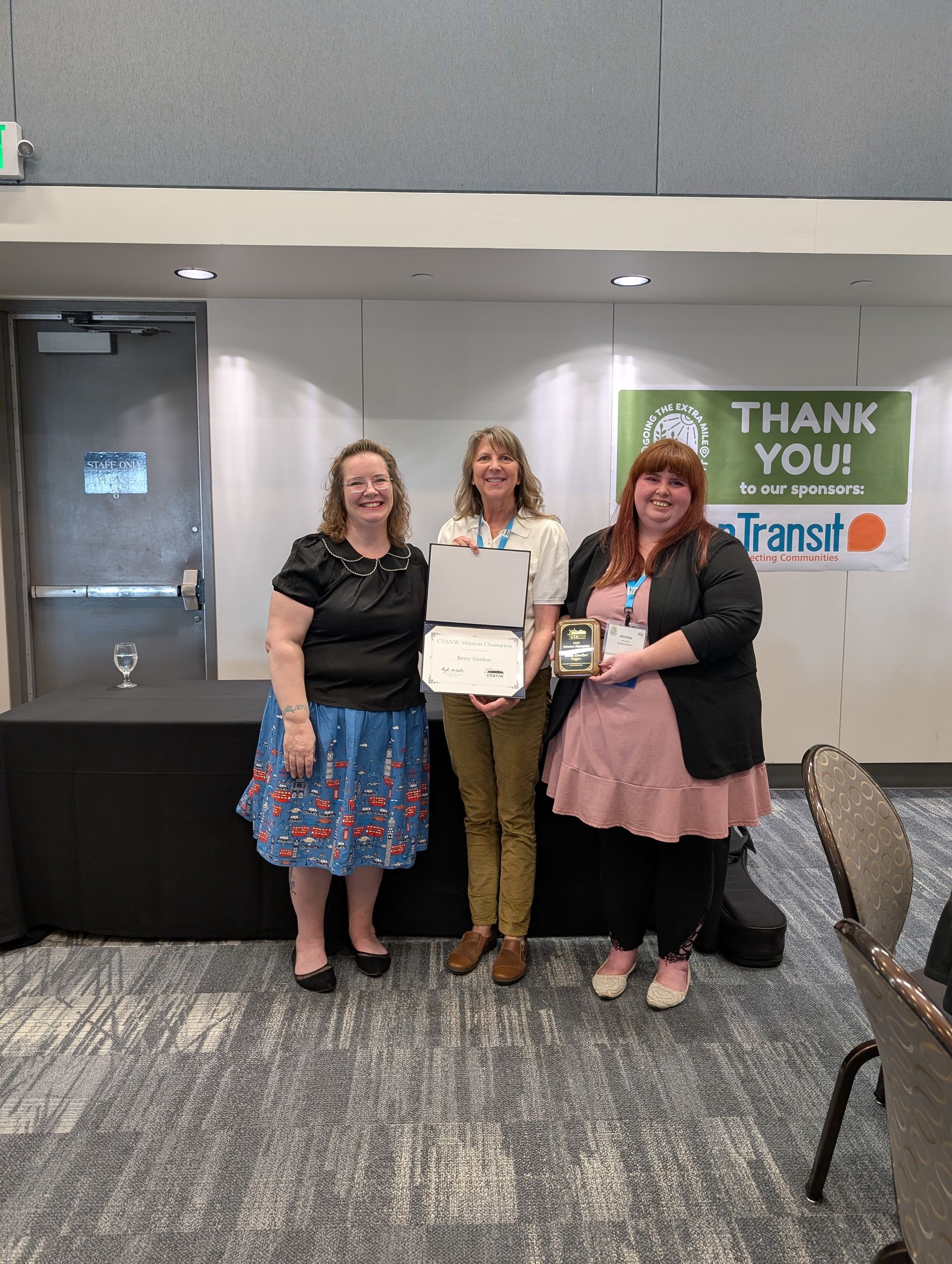 a man and a woman are posing for a picture in a room with tables and chairs .