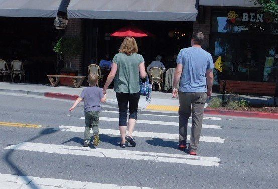 a family crosses a street in front of a store that says ben