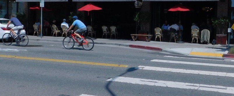 a man is riding a bike down a street in front of a restaurant .