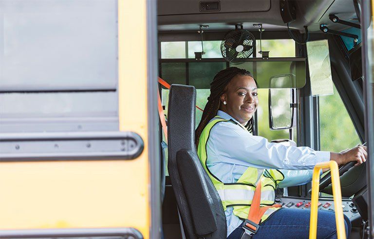 a woman is sitting in the driver 's seat of a school bus .