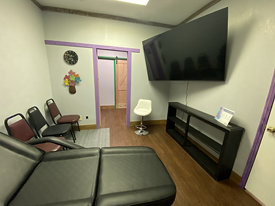 a waiting room with a black chair and a flat screen tv on the wall .