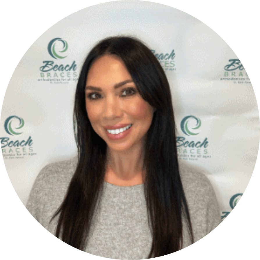 Portrait of a smiling woman with long dark hair in front of a Beach Braces logo backdrop