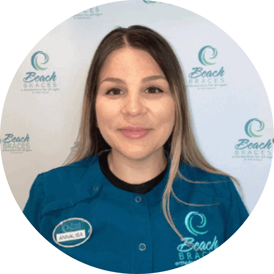 Woman in teal Beach Braces uniform smiling in front of a Beach Braces logo backdrop