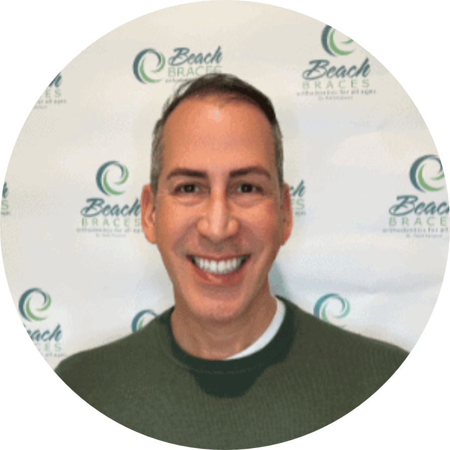 Smiling man in a green sweater standing before a Beach branding backdrop