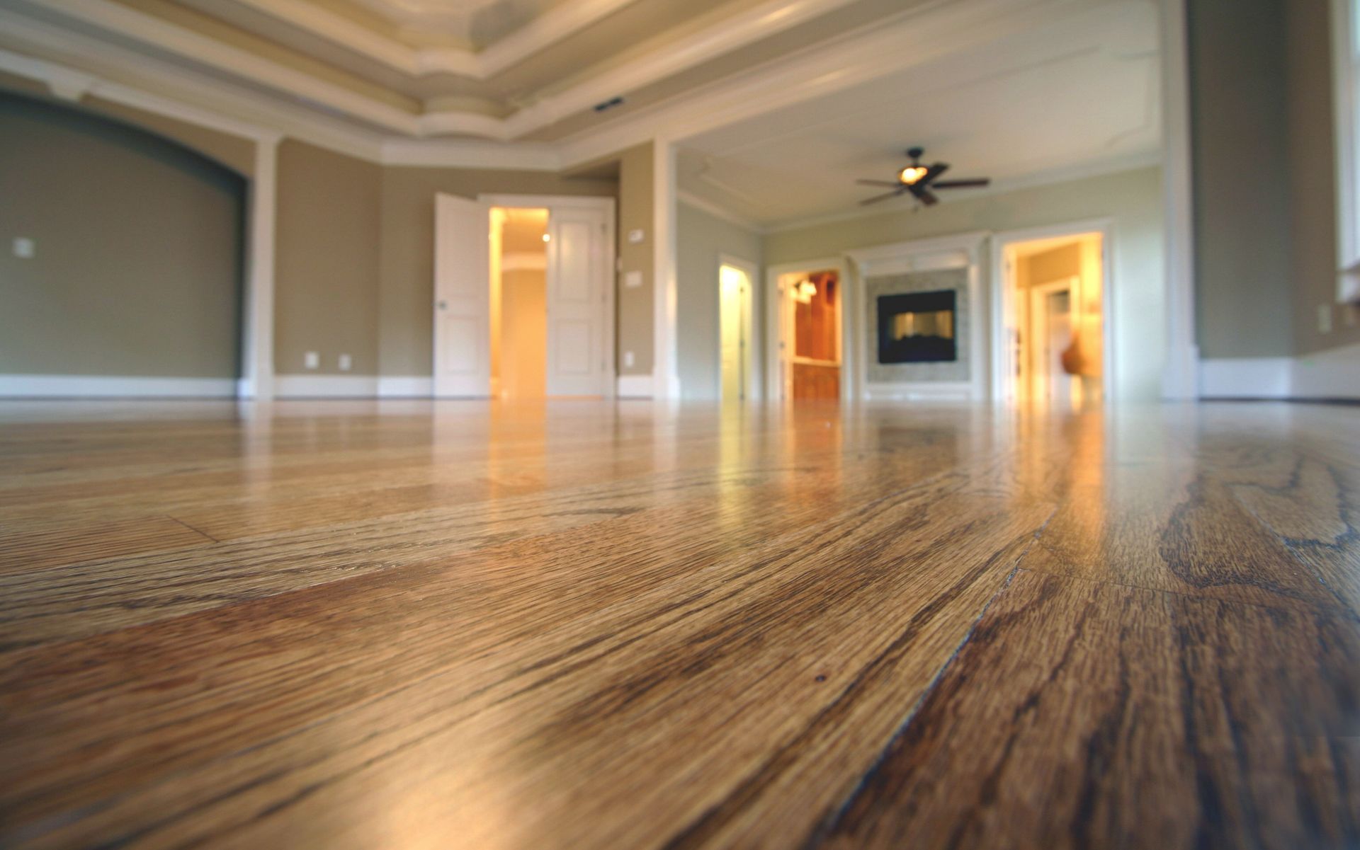 An empty living room with hardwood floors and a ceiling fan.