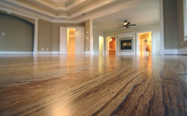 An empty living room with hardwood floors and a ceiling fan.