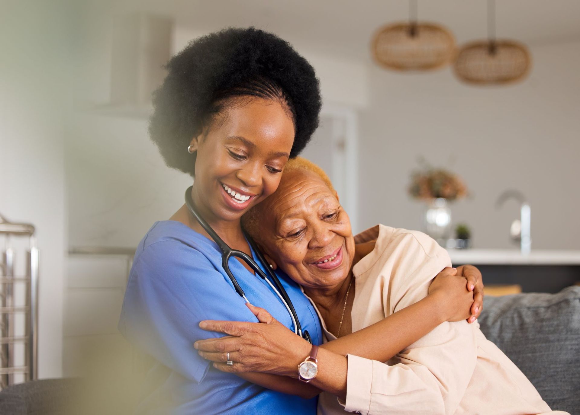 A Nurse Is Hugging An Elderly Woman On A Couch