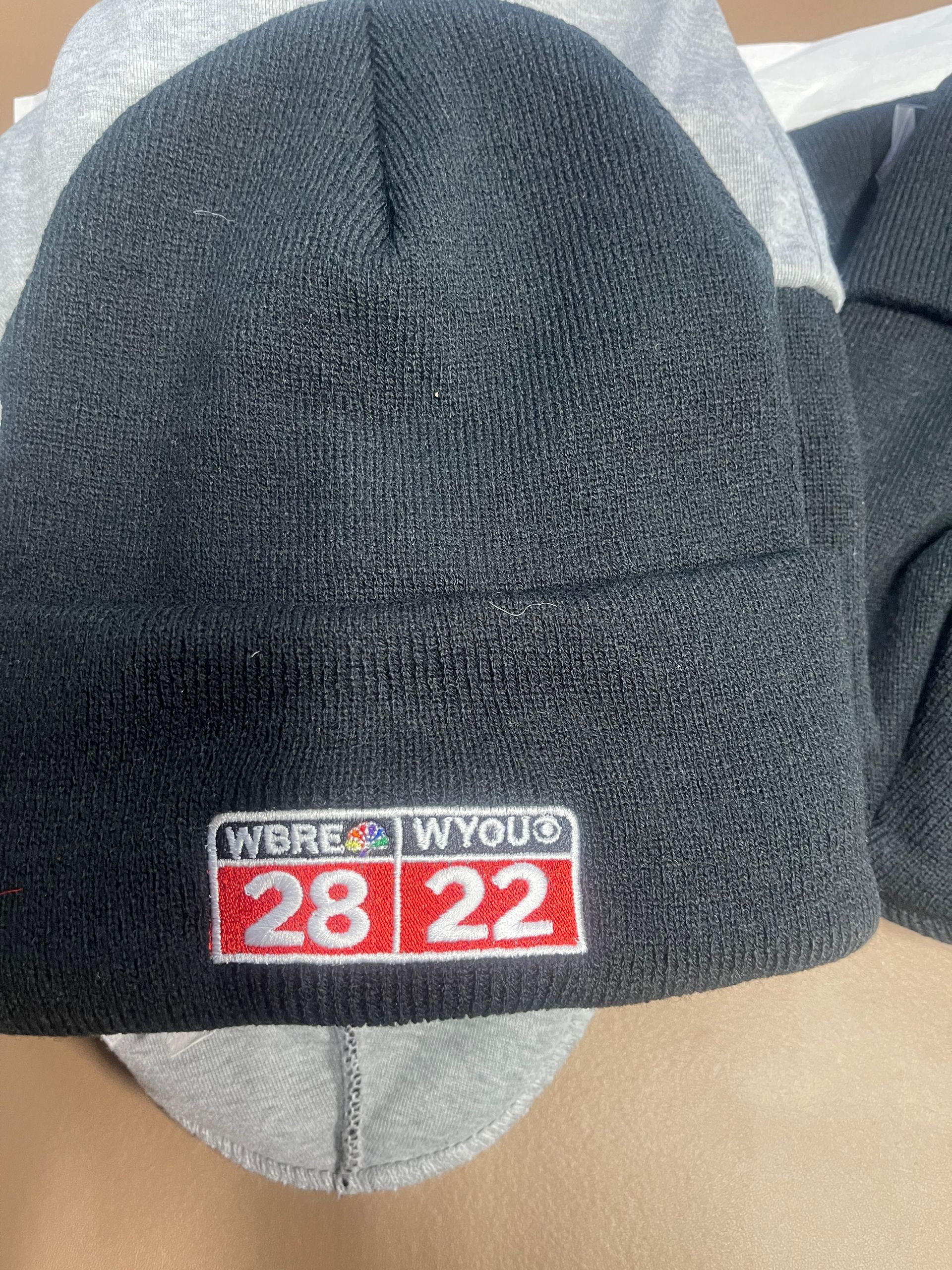 A dark gray knit beanie with a patch reading