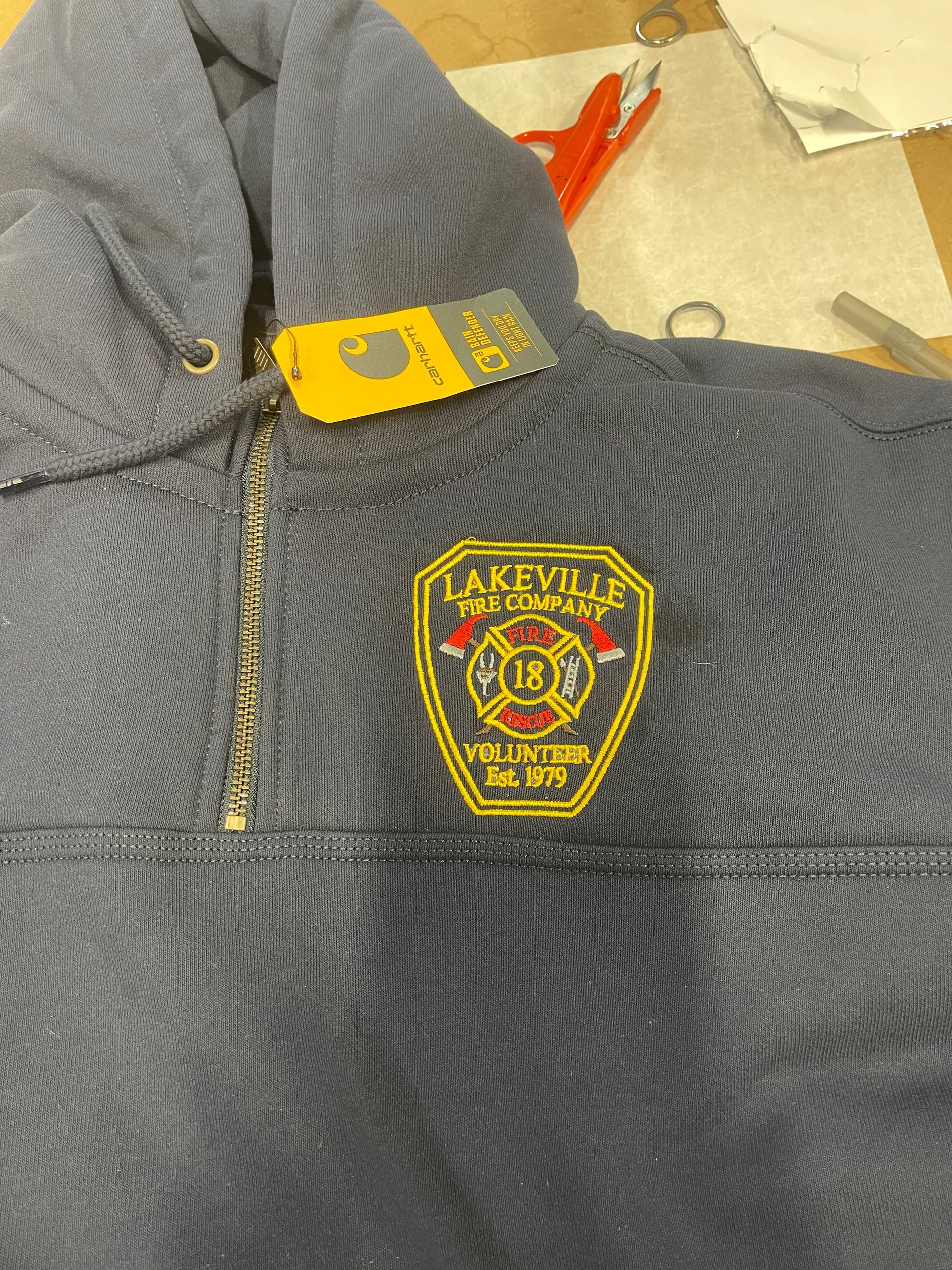 A blue Carhartt hoodie featuring an embroidered Lakeville Fire Department volunteer patch on the chest.
