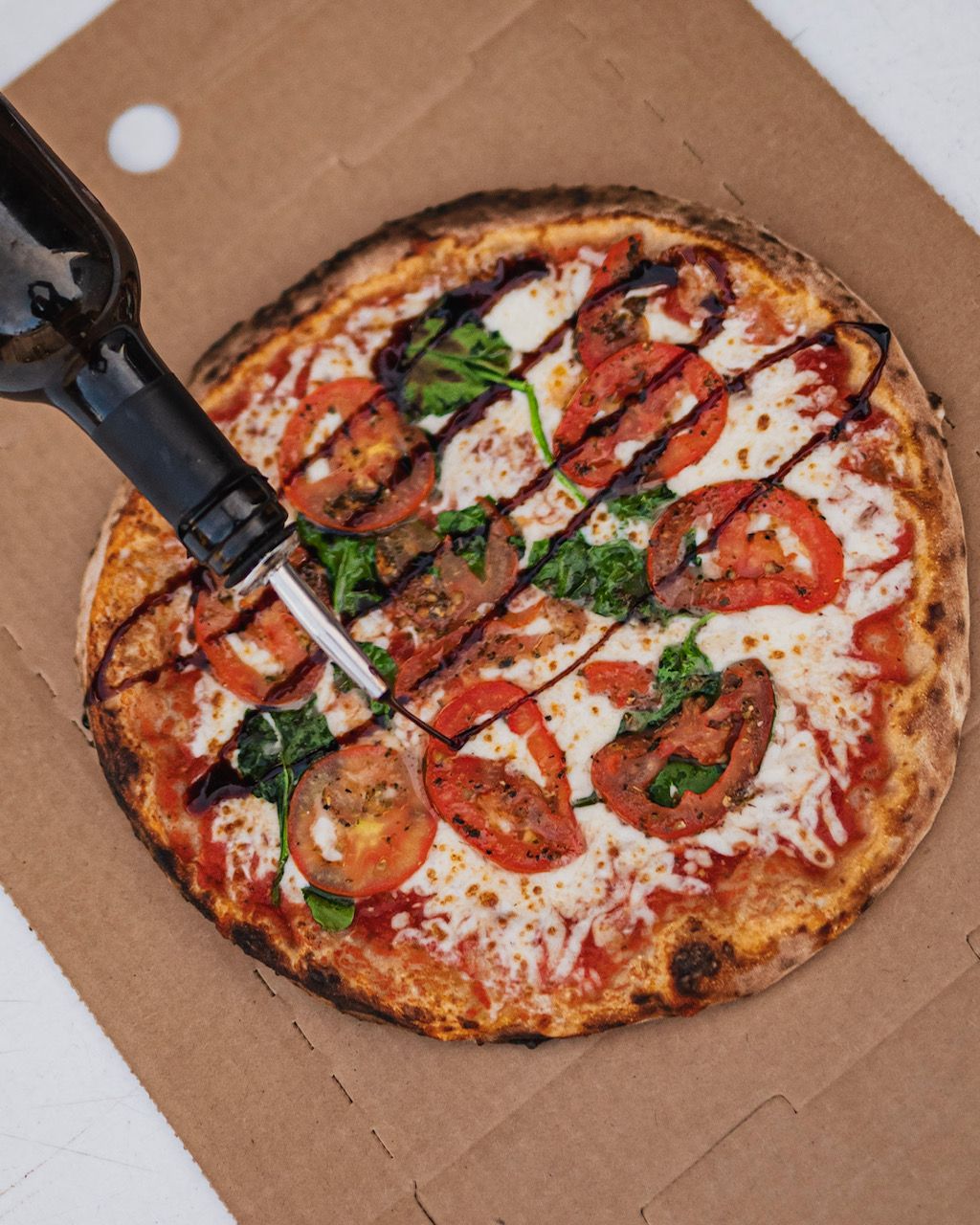 A pizza is being poured with a bottle of wine