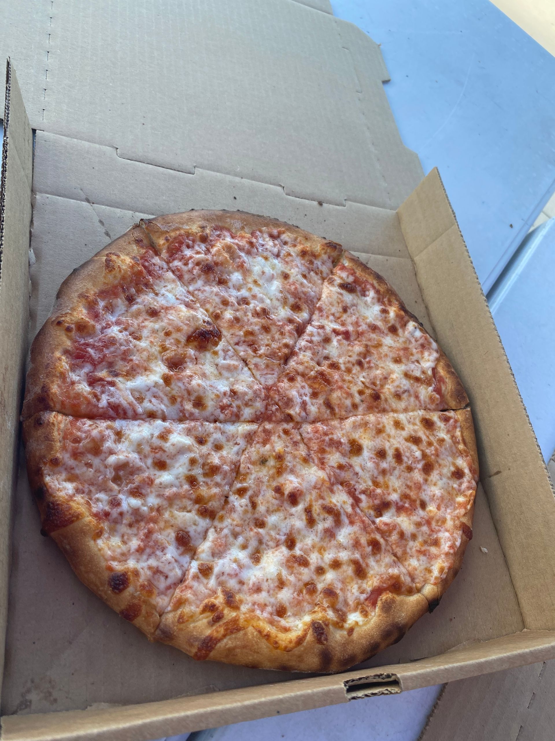 A pizza is sitting in a cardboard box on a table.