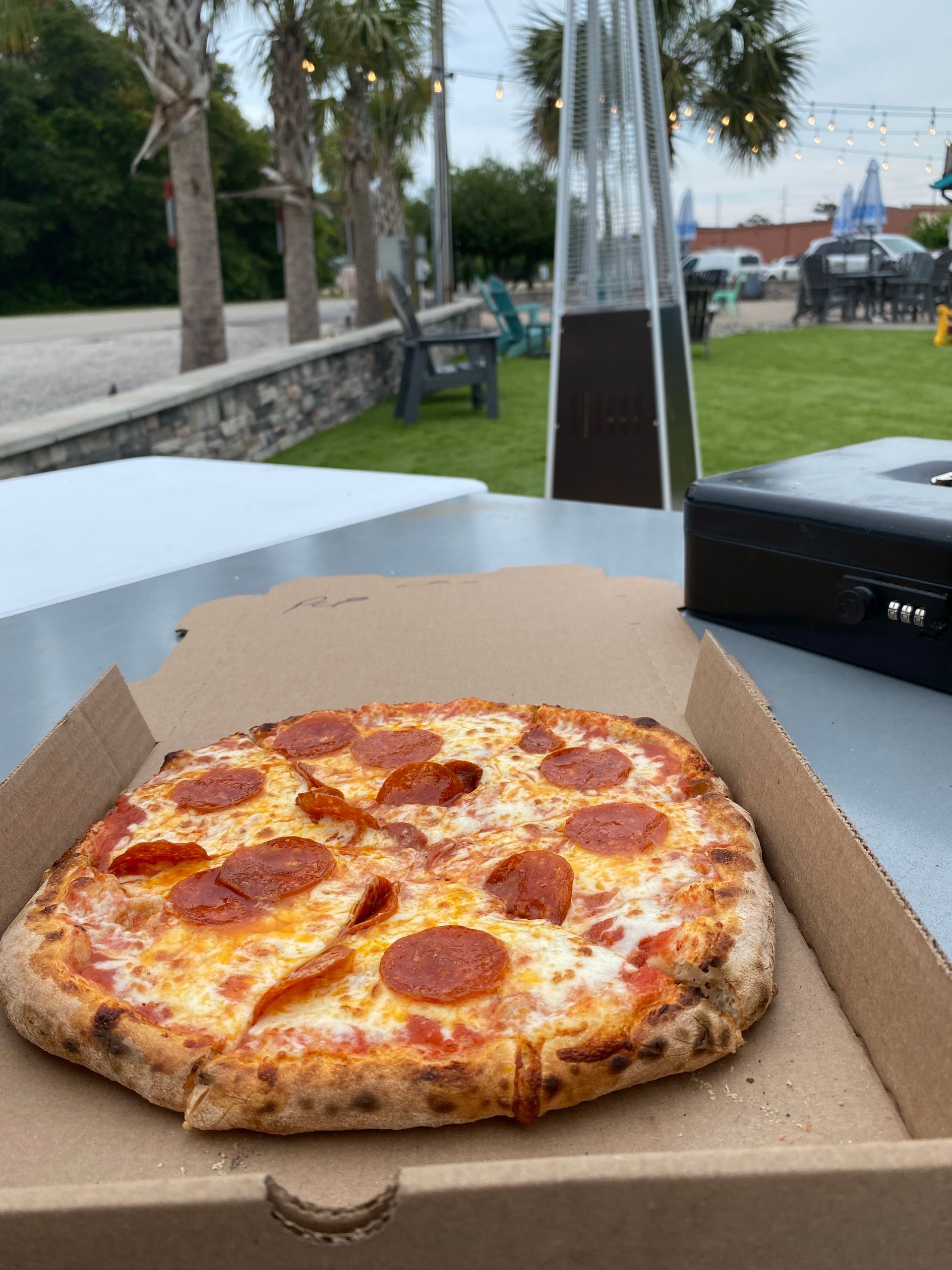 A pepperoni pizza is in a cardboard box on a table.